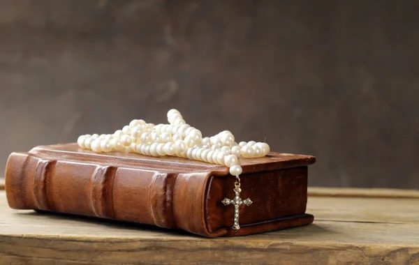 Altes Buch (Bibel) und das christliche Symbolkreuz auf Perlenkette — Stockfoto