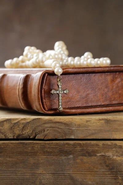 Old book (bible) and the Christian symbol cross on pearl necklace — Stock Photo, Image