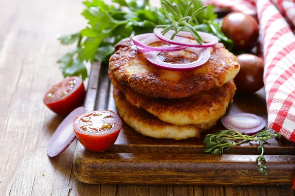 Chuletas fritas con hierbas y cebollas en una tabla de madera — Foto de Stock