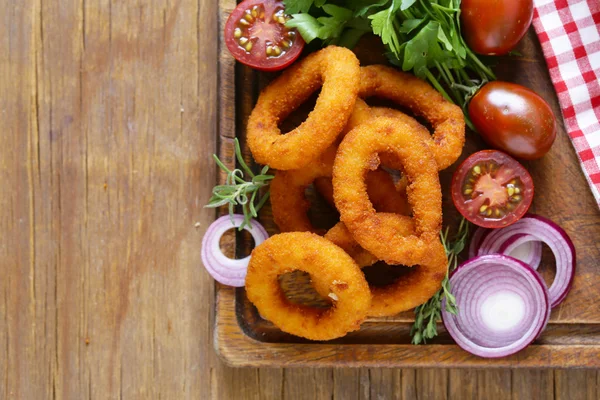 Anéis de cebola fritos em uma mesa de madeira, comida rápida — Fotografia de Stock