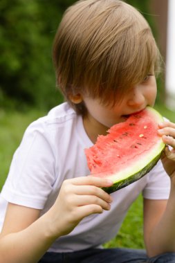 sevimli sarışın çocuk yeşil çayır on kırmızı bir karpuz yiyor