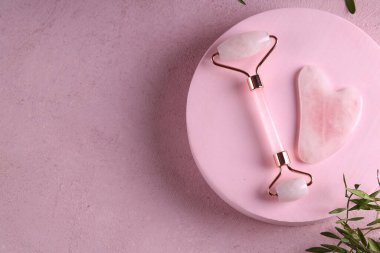 Taş masajcı Guasha, pembe arka planda.