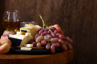 Peynir tabağında ekmek ve masada meyveler.