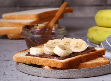 Kahvaltı sandviçleri ve masada muz ve çikolata.