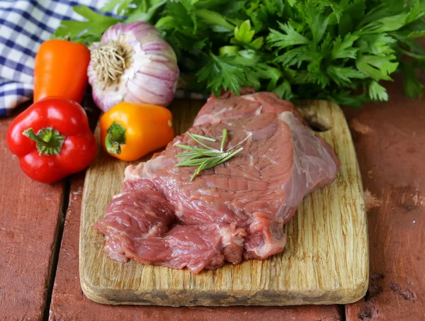 Raw beef steak with ingredients vegetables on a wooden board — Stock Photo, Image