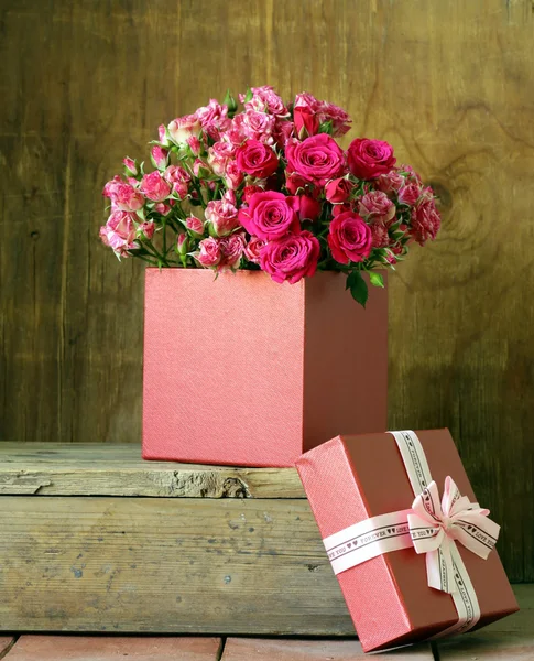 Confezione regalo con mazzo di rose su fondo di legno — Foto Stock