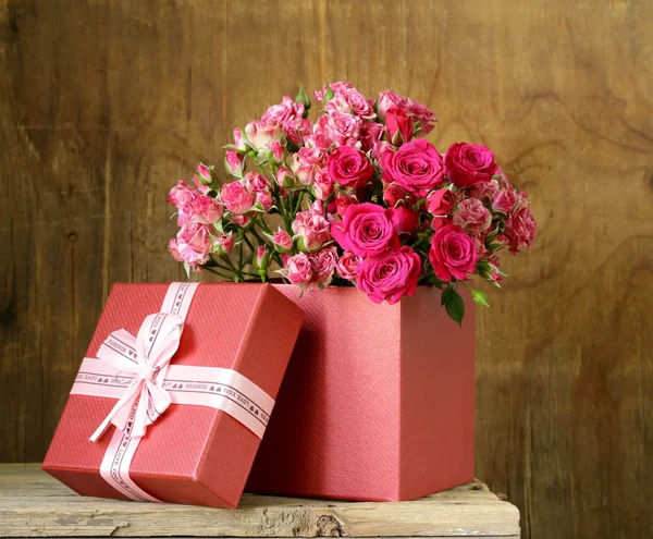 Bouquet of roses with gift box on a wooden background — Stock Photo, Image