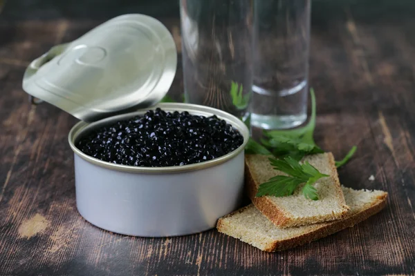 Caviar com pão de centeio e dois tiros de vodka em uma mesa de madeira — Fotografia de Stock