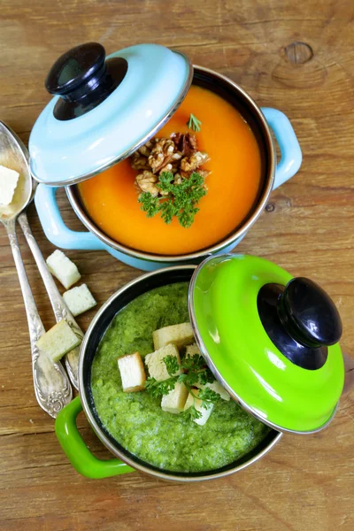 Twee soorten crème soep (broccoli en pompoen) in pot op houten achtergrond — Stockfoto