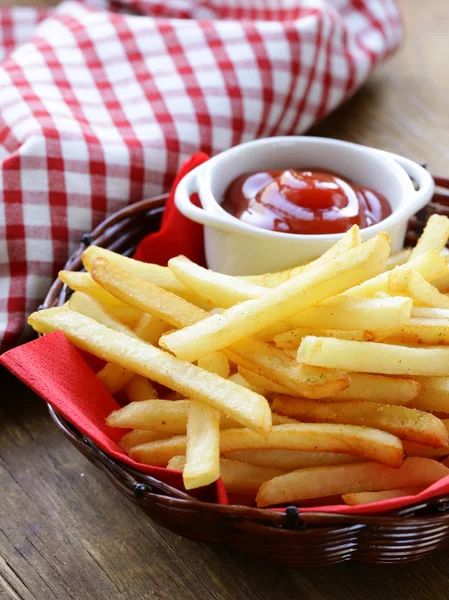 Traditionelle Pommes frites mit Ketchup im Weidenkorb lizenzfreie Stockfotos