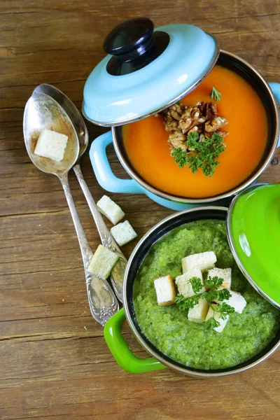 Deux sortes de soupe à la crème (brocoli et citrouille) en pot sur fond en bois — Photo