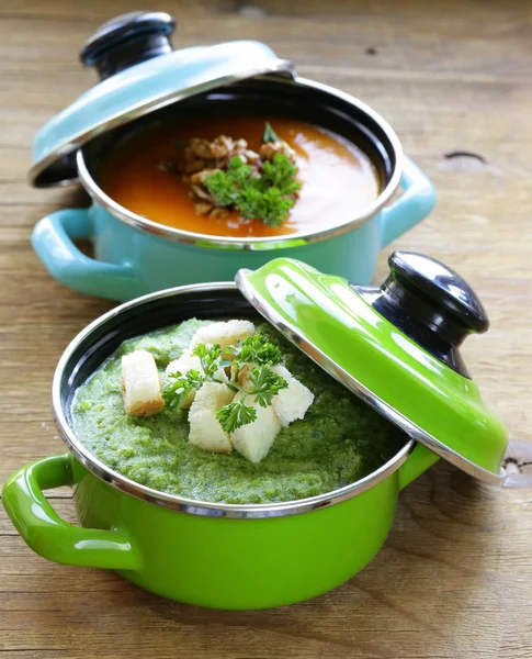 Два види вершкового супу (броколі і гарбуз) в горщику на дерев'яному фоні — стокове фото