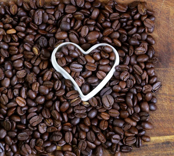 Fundo de grãos de café com um coração branco — Fotografia de Stock