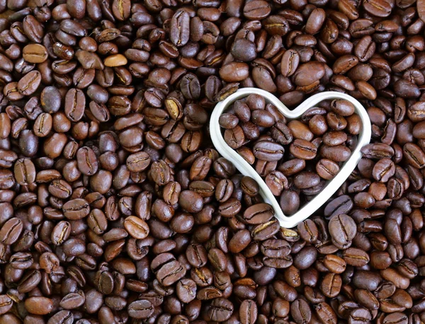 Fundo de grãos de café com um coração branco — Fotografia de Stock