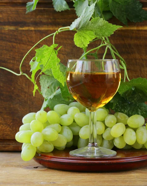 Copo de vinho branco com uvas em um fundo de madeira — Fotografia de Stock