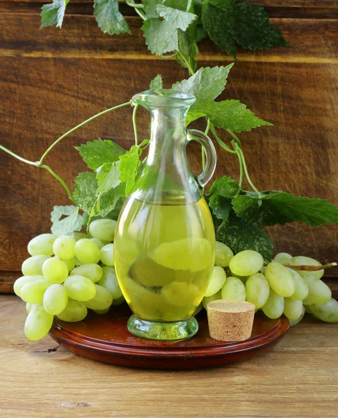 Jugful with grape seed oil on a wooden table — Stock Photo, Image