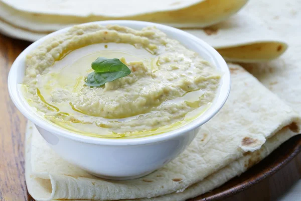 Traditional hummus dip of chickpea with pita bread on a wooden table