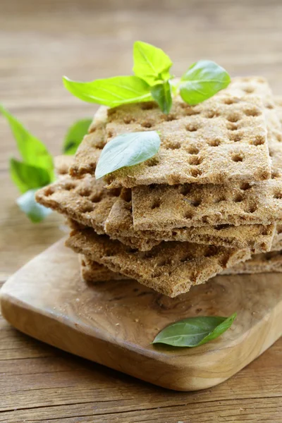 Dry flat bread crisps with herbs on a wooden board — Stock Photo, Image