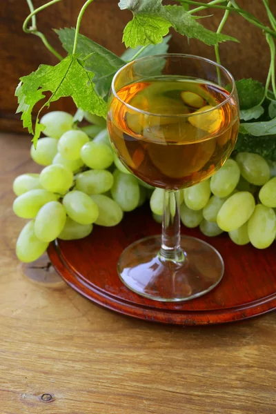 Copo de vinho branco com uvas em um fundo de madeira — Fotografia de Stock