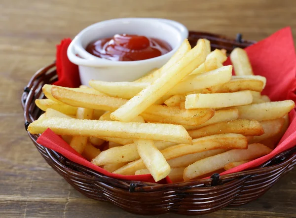 Traditional French fries with ketchup in a wicker basket — Stock Photo, Image