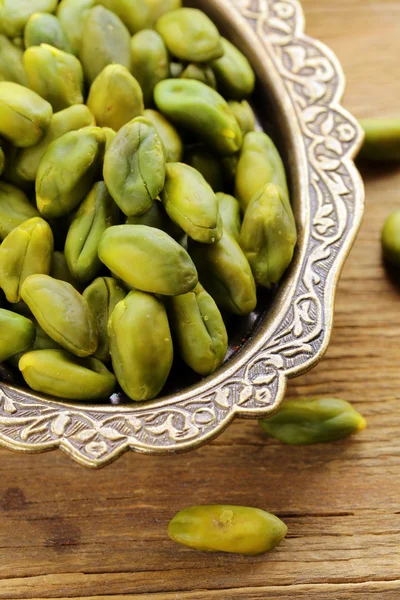 Peeled green pistachio nuts on a wooden background — Stock Photo, Image