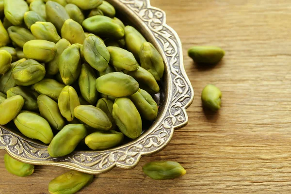 Peeled green pistachio nuts on a wooden background — Stock Photo, Image