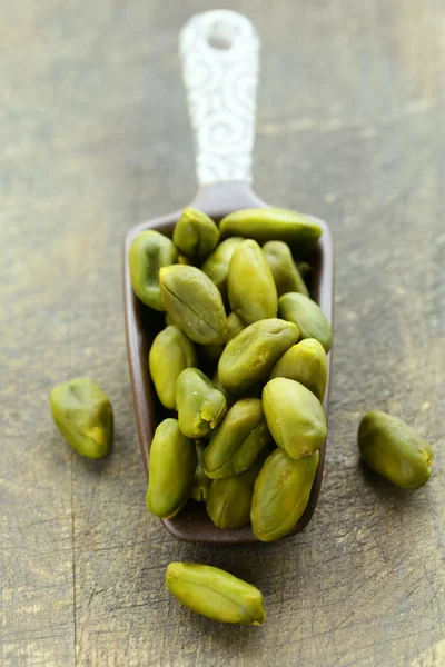 Peeled green pistachio nuts on a wooden background — Stock Photo, Image