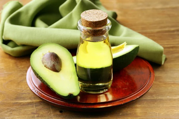 Oil of avocado and fresh fruit on wooden table — Stock Photo, Image