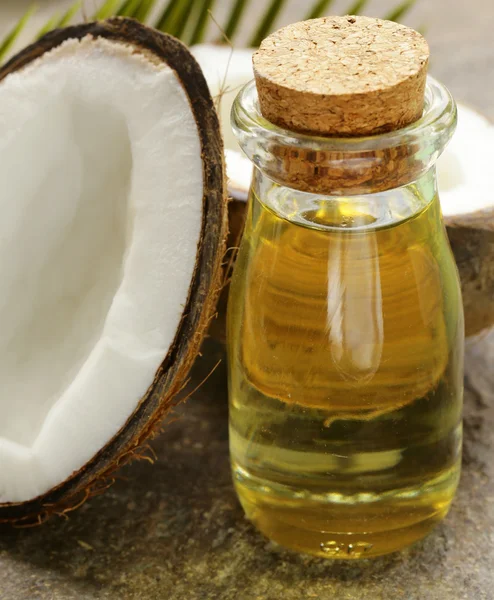 Coconut oil in a glass bottle and fresh nuts — Stock Photo, Image