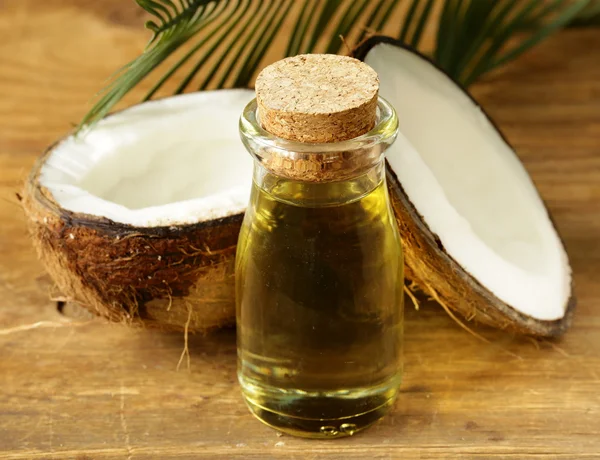 Coconut oil in a glass bottle and fresh nuts — Stock Photo, Image