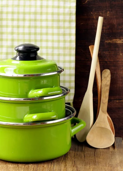 Set of metal green pots cookware on a wooden background — Stock Photo, Image