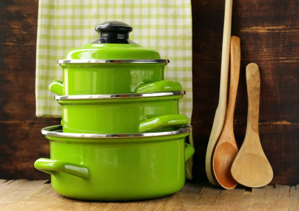 Set de ollas de metal verde utensilios de cocina sobre un fondo de madera —  Fotos de Stock