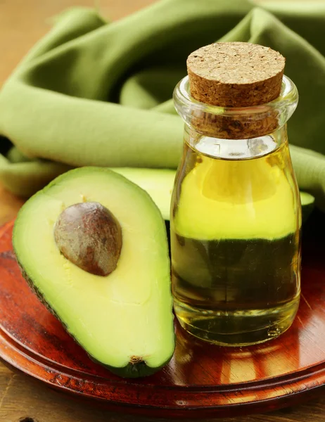 Oil of avocado and fresh fruit on wooden table — Stock Photo, Image