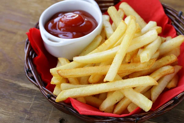 Papas fritas tradicionales con ketchup en una canasta de mimbre —  Fotos de Stock