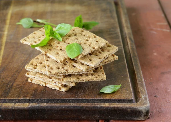 Dry flat bread crisps with herbs on a wooden board — Stock Photo, Image