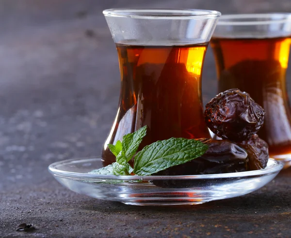 Turkish tea in traditional glass with sweet dates — Stock Photo, Image