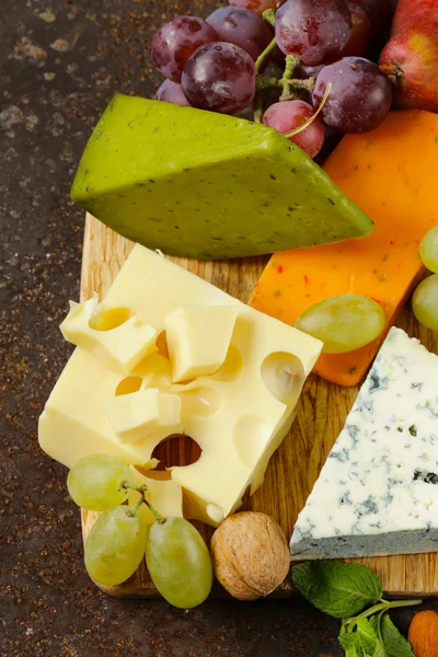Planche à fromage avec différents types de fromages et de raisins — Photo