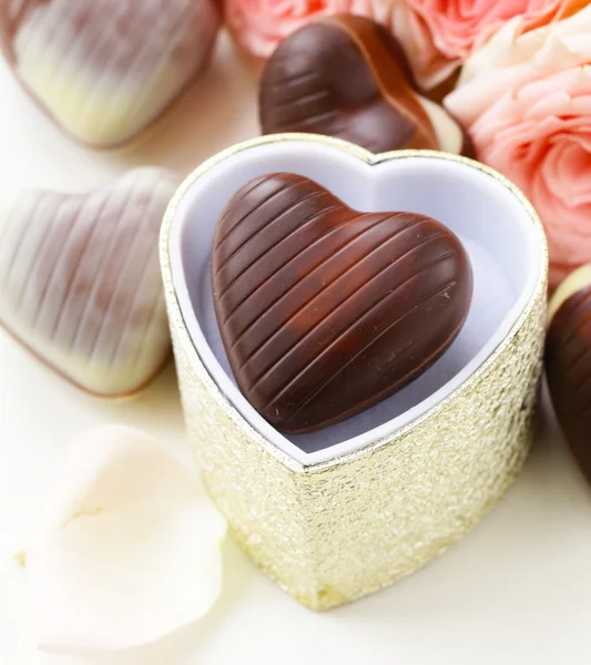 Chocolate candy in the shape of hearts and pink roses for Valentine's day holiday — Stock Photo, Image