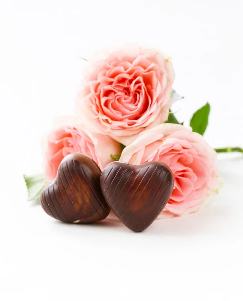 Chocolate candy in the shape of hearts and pink roses for Valentine's day holiday — Stock Photo, Image