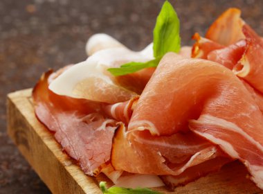 Ahşap oyun tahtası fesleğen yaprakları ile jambon füme jamon (Parma)