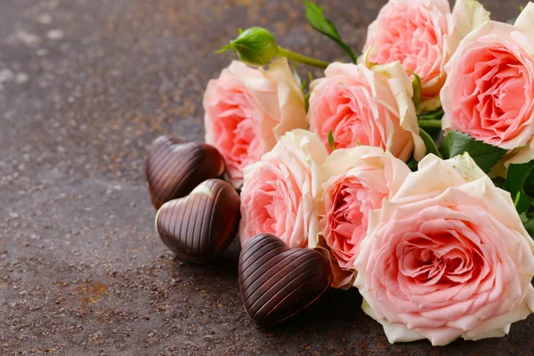 Čokoládové bonbóny srdce a růžové růže na Valentýna svátek — Stock fotografie