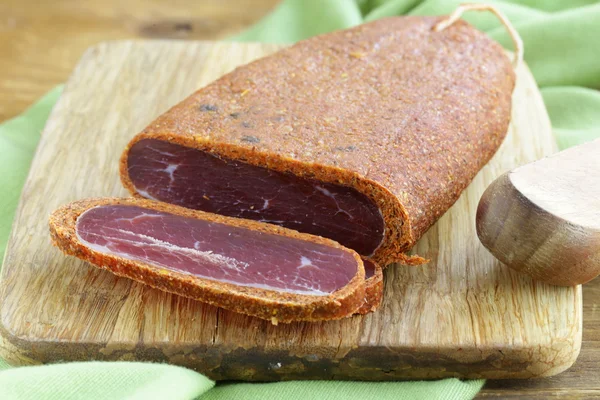 Carne curada - basturma em pimentão quente (páprica) em uma tábua de corte — Fotografia de Stock