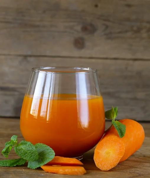 Fresh carrot juice in glass on a wooden table — Stock Photo, Image