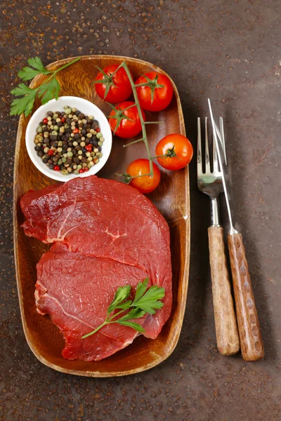 Свежее говяжье мясо с перцем и травами на деревянной тарелке — стоковое фото