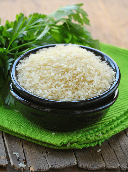 Natural organic white rice in bowl on a wooden background