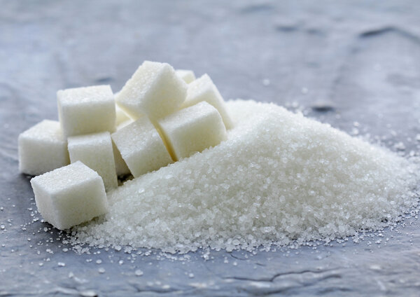 White granulated sugar and refined sugar on a gray background