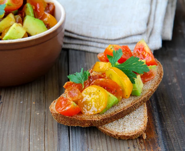 Traditional Italian appetizer of bruschetta with tomato and avocado — Stock Photo, Image