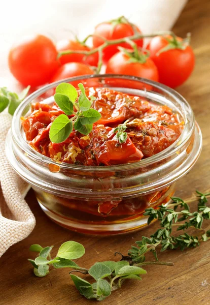 Sun-dried tomatoes with herbs in a glass jar — Stock Photo, Image