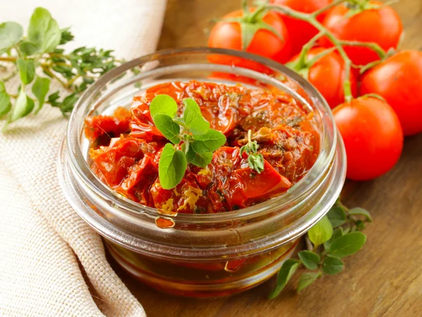 Sun-dried tomatoes with herbs in a glass jar — Stock Photo, Image