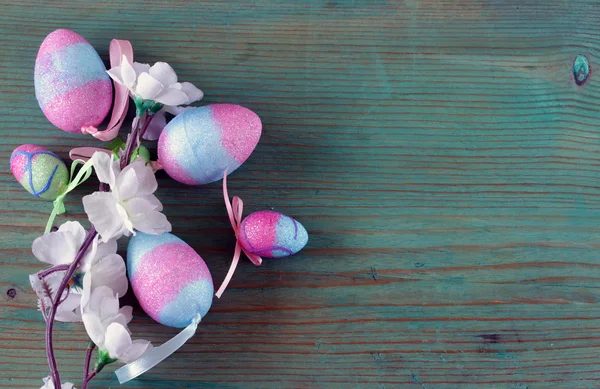 Colorful decorative easter eggs and branch with spring flowers on the old wooden background — Stock Photo, Image